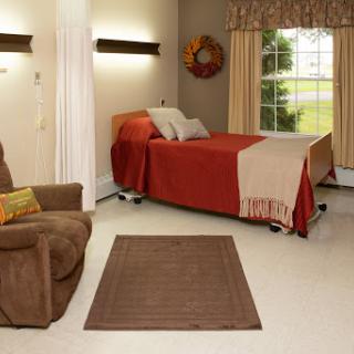 A cozy and well-decorated bedroom featuring a comfortable bed, an armchair, and warm lighting.