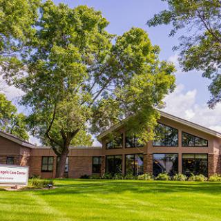 A modern building surrounded by lush green grass and trees.