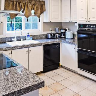 A modern kitchen featuring white cabinets, granite countertops, and a double oven.