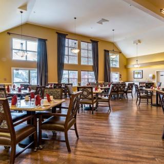 A spacious and elegantly decorated dining room with wooden floors, set for guests.