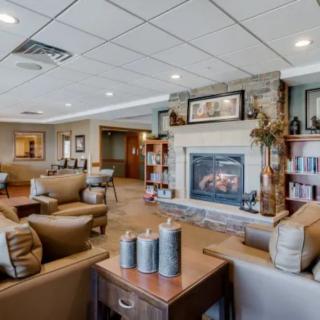 A cozy living room with a fireplace, comfortable seating, and bookshelves.