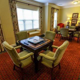 A cozy living room with a central table and chairs, featuring warm lighting and elegant decor.