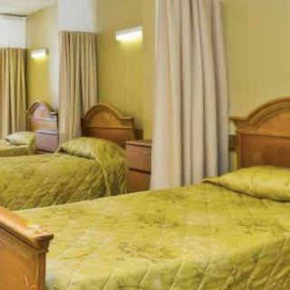 A cozy hotel room featuring two twin beds with green bedding and wooden headboards.