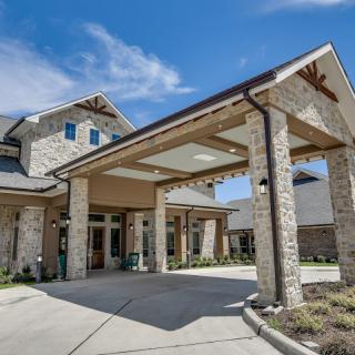 A modern stone building with a covered entrance and driveway.