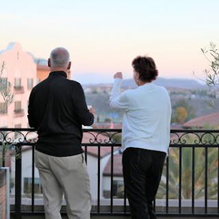 A couple enjoys a scenic view from a balcony during sunset.