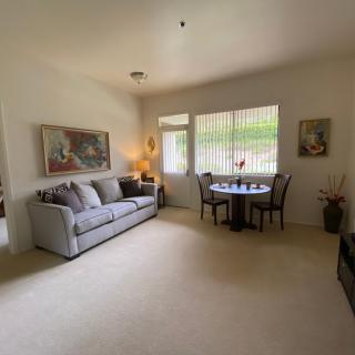 A cozy living room with a sofa, dining table, and artwork on the walls.