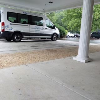 A white van parked in a shaded area under a building.