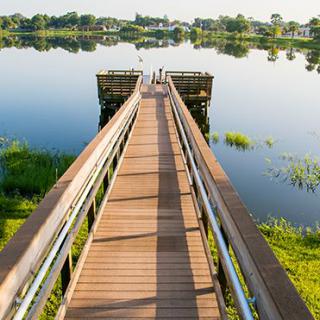 A tranquil dock extending over a serene lake with clear reflections of the surrounding landscape.