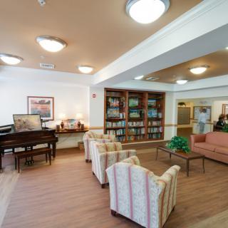 A cozy lobby with a seating area, piano, and bookshelves.