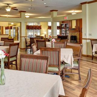 A spacious dining area with neatly arranged tables and chairs, featuring wooden floors and soft lighting.