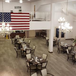A spacious dining area with elegant chandeliers and a prominent American flag displayed on the wall.