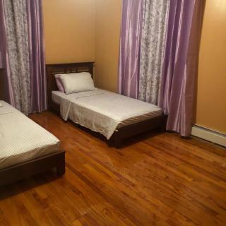 A simple bedroom with two single beds and wooden flooring.