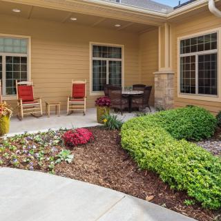 A cozy patio with rocking chairs and a neatly landscaped garden.