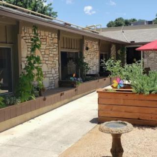 A sunny patio with stone walls, raised planter boxes, and a red umbrella.