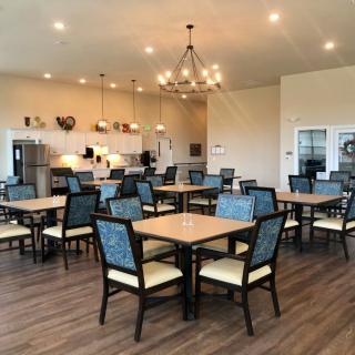 A spacious dining area with multiple tables and chairs, featuring a chandelier and modern decor.