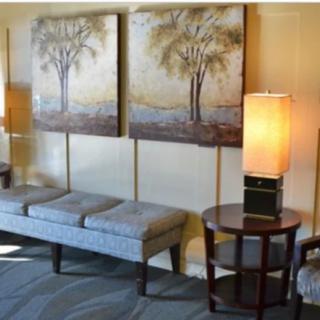 A cozy interior space with a bench, side table, lamps, and artwork on the wall.