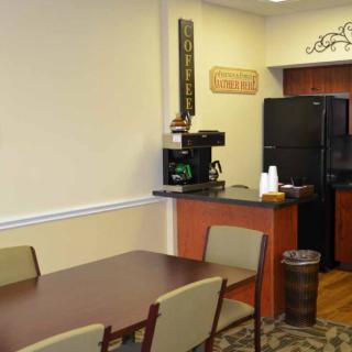 A cozy kitchen and dining area with a table, chairs, coffee machine, and refrigerator.