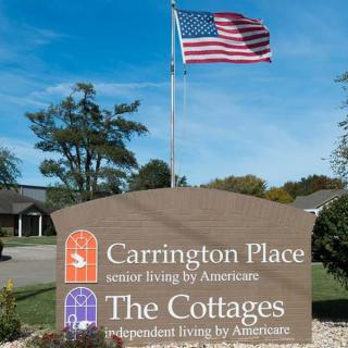 A sign for Carrington Place, a senior living community, with an American flag flying above it.