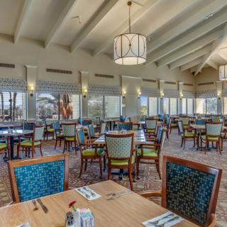 A spacious restaurant interior with neatly arranged tables and chairs, featuring large windows and stylish lighting.