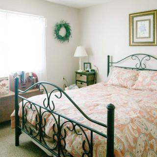 A cozy bedroom with an iron bed, decorative bedding, and a warm, inviting atmosphere.