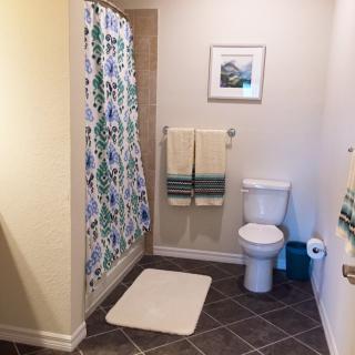 A clean and organized bathroom featuring a shower with a colorful curtain, a toilet, and neatly arranged towels.
