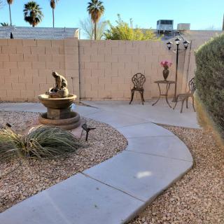 A peaceful garden patio featuring a decorative fountain and seating area with palm trees in the background.