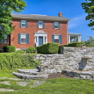 A charming brick house surrounded by lush greenery and stone landscaping.
