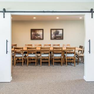A conference room with a long wooden table and multiple chairs, set up for a meeting.