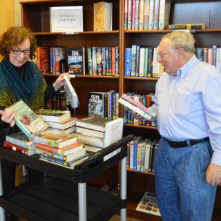 Two people organizing a collection of books in a library setting.