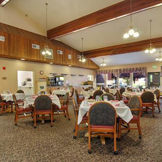 An elegant dining area with neatly arranged tables and chairs, featuring warm lighting and a cozy atmosphere.