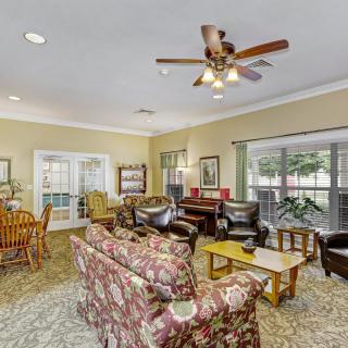 A cozy living room with a ceiling fan, sofas, and large windows.