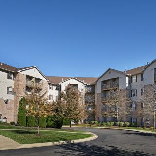 A suburban apartment complex with landscaped surroundings under a clear blue sky.
