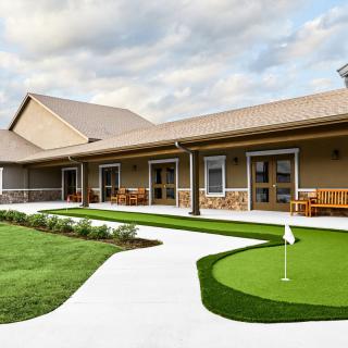 A building with a putting green and landscaped pathway.