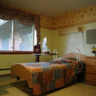 A cozy bedroom with a single bed, wooden furniture, and a window with curtains.
