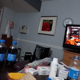 A view of a hospital room with medication, snacks, and a television.