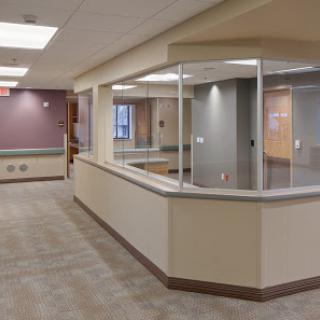 A modern and spacious healthcare reception area featuring glass partitions and soft color tones.