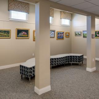 A small indoor art gallery with paintings on the walls and modern seating arrangements.