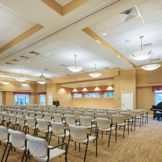 A spacious conference room with rows of chairs facing a stage, suitable for meetings or events.