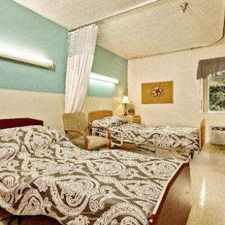 A cozy hospital room featuring two neatly made beds and soft lighting.