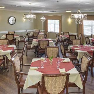 An elegantly set dining room with tables and chairs, adorned with chandeliers.