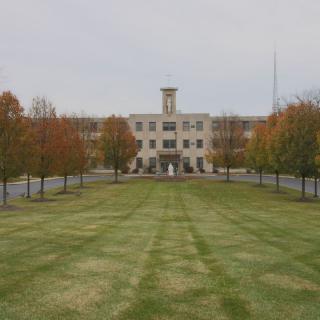 A symmetrical view of a building surrounded by autumn trees and a well-maintained lawn.