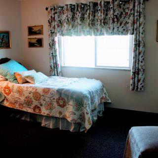 A cozy bedroom with two single beds, floral bedding, and a window with patterned curtains.