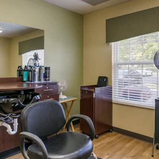A well-lit hair salon interior with a styling chair, mirror, and hairstyling tools.