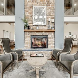 A cozy living room featuring a brick fireplace, surrounded by elegant armchairs and a central coffee table.