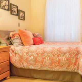 A cozy bedroom with a neatly made bed adorned with colorful pillows and decorative bedding.