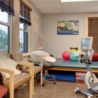 A physical therapy room equipped with exercise equipment and seating.