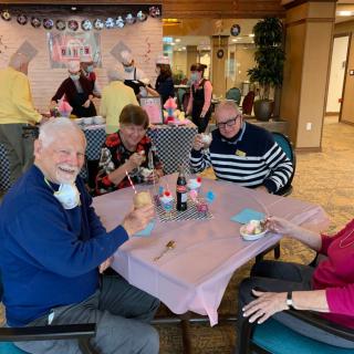 A group of elderly people enjoying ice cream at a social gathering indoors.