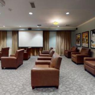A cozy home theater room with leather seating and a large projector screen.