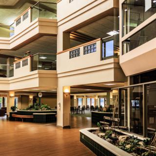 A modern lobby with multiple levels, featuring sleek architectural design and indoor plants.
