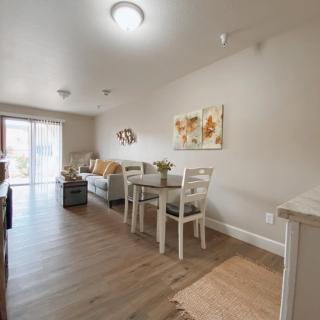 A modern apartment interior featuring a combined living and dining area with wooden flooring and contemporary furniture.